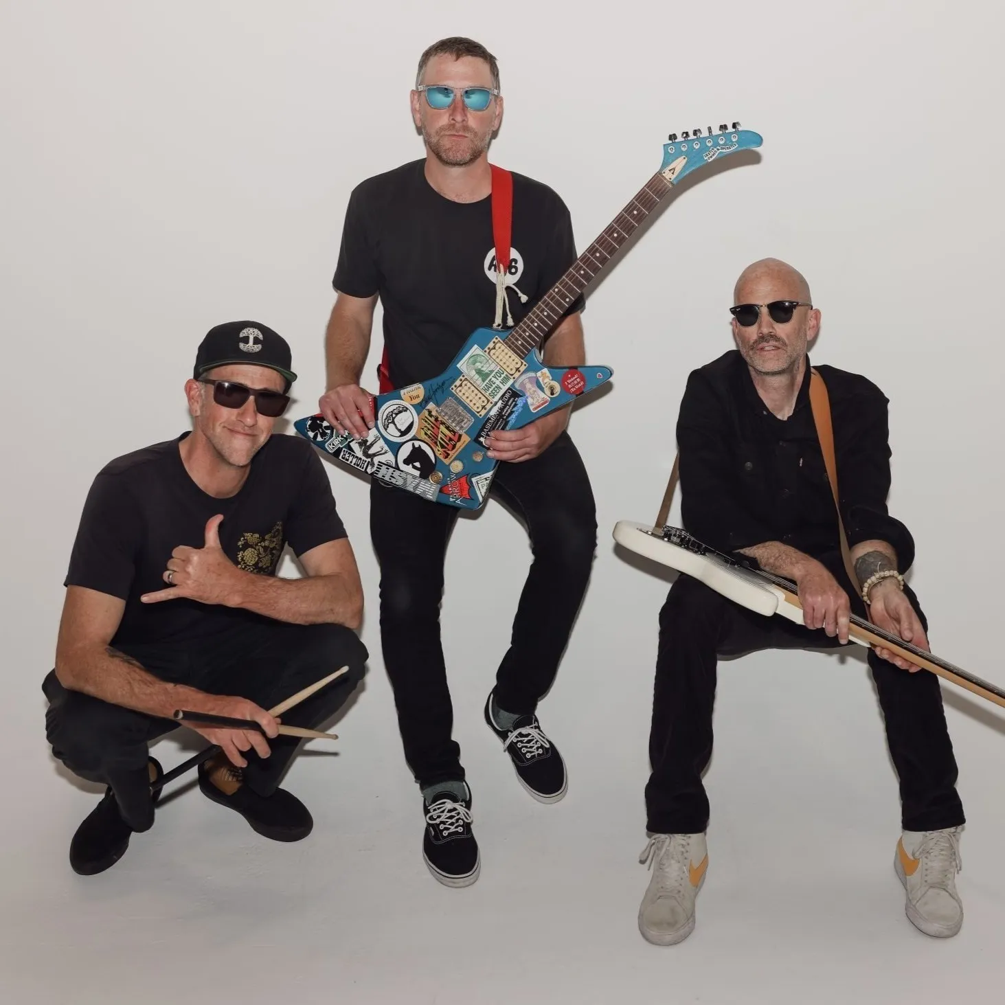 Torpedo Wharf posing against a white wall, guitars in hand